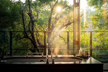 Singita Sweni Lodge: Freistehende Badewanne vor sonnigem Waldpanorama