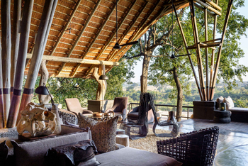 Singita Boulders Lodge: Offenes Lounge mit Wicker-Möbeln und Ausblick