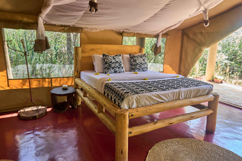 Tindiga Tented Camp: Schlafzimmer mit Holzrahmenbett und Blumenarrangement