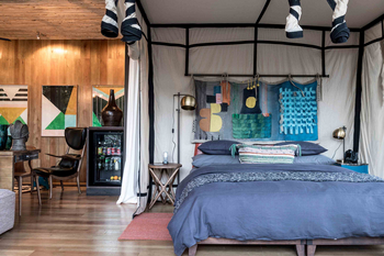 Singita Sweni Lodge: Safari-Schlafzimmer mit bunter Textilkunst und Lederliege