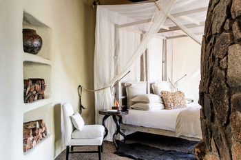 Singita Boulders Lodge: Schlafzimmer mit Himmelbett und Ast-Tisch