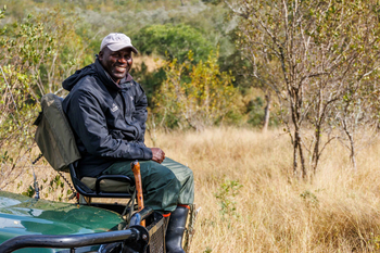 Savanna Lodge: Gast lächelnd auf Safari-Jeep im Busch