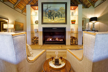 Savanna Lodge: Gemütliche Lounge mit Kaminfeuer und Sesseln