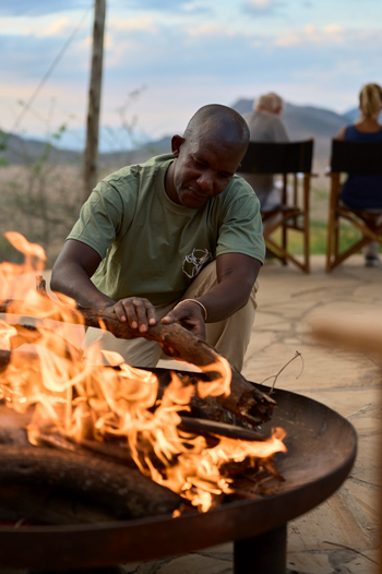 Mkomazi Wilderness Retreat: Guide schürt knisterndes Feuer bei Abendrot