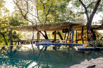 Singita Boulders Lodge: Outdoor-Lounge am Pool im Sonnenlicht