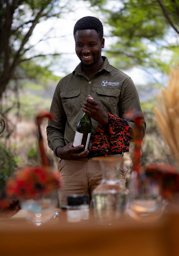 Mkomazi Wilderness Retreat: Lächelnder Mitarbeiter beim Wein-Service im Busch