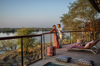 Anantara Tented Camp Kafue River: Gäste mit Sundowner auf Holzdeck am Fluss