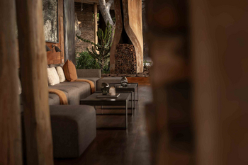 Singita Lebombo Lodge: Lounge mit grauem Ecksofa und Holzsäule
