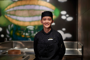 Scenic Eclipse II: Lächelnder Koch vor Kunstwand