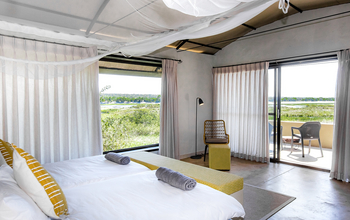 Serondela Lodge: Schlafzimmer mit Doppelbett, senfgelben Kissen und Bank