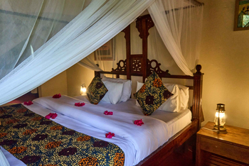 Arusha Safari Lodge: Rustikales Bett mit Moskitonetz und Ornamenten