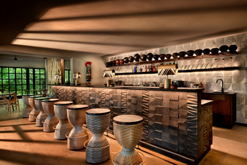 andBeyond Phinda Forest Lodge: Bar mit geflochtenen Hockern und goldener Nachmittagssonne