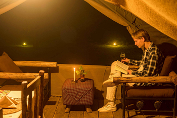 Ikoma Tented Camp: Gast mit Wein im Abendlicht lesend
