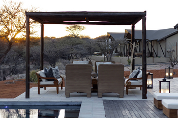 Otjiwa Thornbush Tented Camp: Pergola-Lounge mit Korbsesseln im warmen Buschabend