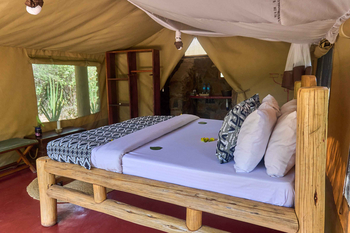 Tindiga Tented Camp: Schlafzimmer mit Naturholzrahmenbett und Blüten