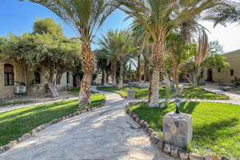 Fort Sesfontein Lodge: Palmengarten mit rustikalem Steinpfad im Morgenlicht