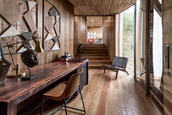 Singita Sweni Lodge: Edler Holzschreibtisch mit Schachspiel und Maskenskulptur