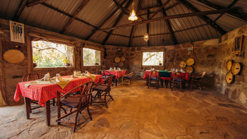 Tindiga Tented Camp: Safari-Esszimmer mit roten Tischdecken und Natursteinwänden