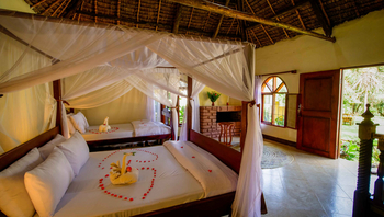 Arusha Safari Lodge: Zwei Himmelbetten mit Blüten und Kamin