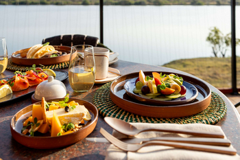 Anantara Tented Camp Kafue River: Gedeckter Holztisch mit Früchtefrühstück am Flussufer