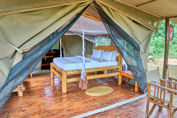 Migunga Tented Camp: Moskitonetz über Bett mit Blütenarrangement
