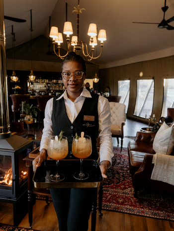 Otjiwa Thornbush Tented Camp: Mitarbeiter serviert Sundowner-Cocktails in Kaminlounge